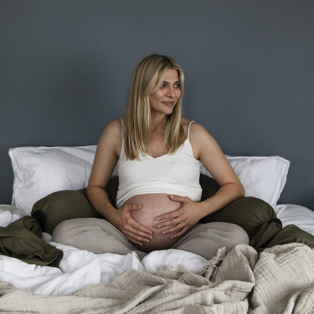Camilla sitter i sengen med gravid mage og gravidepute fra bbhugme